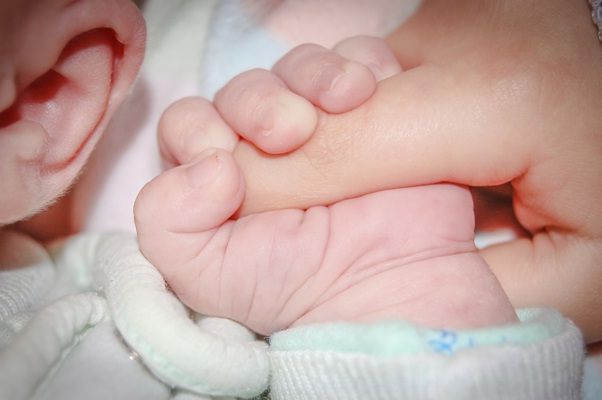 new born baby holding finger of parent (Surrogacy)
